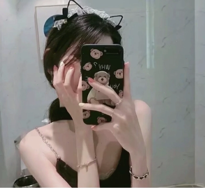 Cô gái xinh đẹp nhìn vào gương và dùng điện thoại che mặt